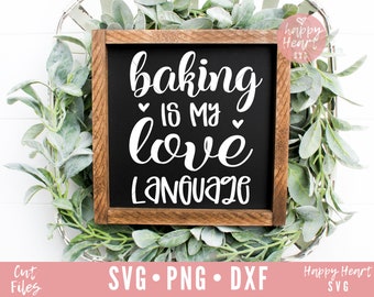 May include: A black chalkboard sign with a wooden frame, featuring the text "baking is my love language" in white cursive font with two small hearts.