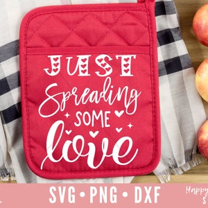 May include: Red quilted pot holder with the text "JUST Spreading some love" in white with small hearts around the letters.