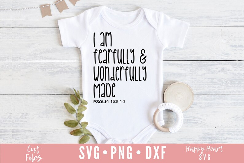 Op de afbeelding: Witte baby romper met zwarte tekst die "Ik ben ontzaglijk en wonderbaarlijk gemaakt PSALM 139:14" luidt.