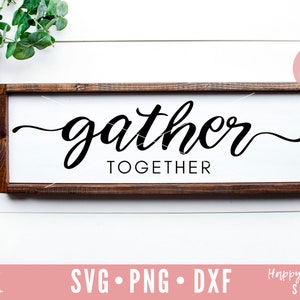 Puede incluir: Un letrero de madera con el texto "gather together" en una fuente cursiva negra. El letrero está sobre un fondo de madera blanca.