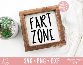 May include: A wooden sign with the text "FART ZONE" in black lettering on a white background. The sign is framed in a dark brown wood frame.