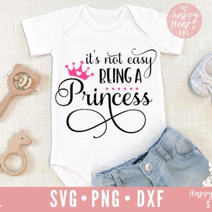 May include: White baby onesie with a pink crown and the text "it's not easy being a princess".