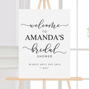 May include: White welcome sign with black text that reads "Welcome to Amanda's Bridal Shower 30 Days Until She Says "I Do!"
