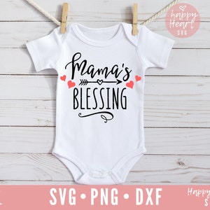 Op de afbeelding: Een witte baby romper met zwarte tekst die "Mama's Blessing" zegt met een pijl en een hart. Er zijn kleine rode hartjes rond de tekst.