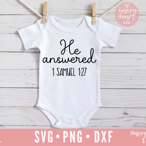 Op de afbeelding: Witte baby romper met zwarte tekst die "Hij antwoordde 1 Samuel 1:27" luidt.