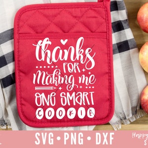 May include: Red quilted pot holder with white text that reads "Thanks for making me one smart cookie". The text is in a handwritten font with a pencil and hearts as accents.