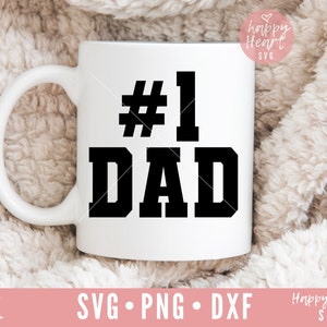 K&ouml;nnte beinhalten: Eine wei&szlig;e Keramiktasse mit einer schwarzen Grafik, auf der in fetter Schrift "#1 DAD" steht.