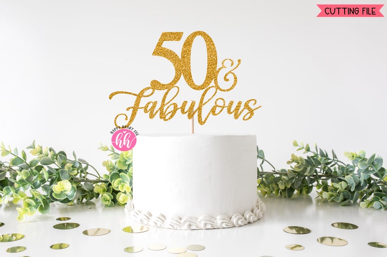 May include: A white cake with a gold glitter cake topper that reads "50 & Fabulous." The cake is decorated with white frosting and sits on a white surface. Greenery and gold confetti surround the cake. The image also includes the text "CUTTING FILE."