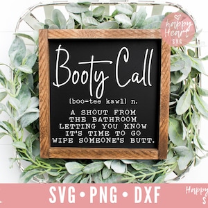 May include: A black framed sign with the text "Booty Call" and a definition of the term. The sign is sitting on a bed of green leaves.