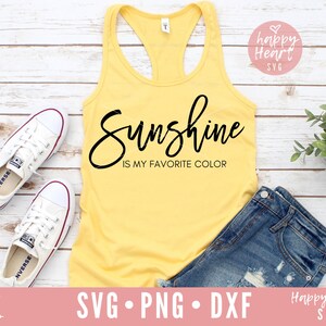 May include: A yellow tank top with the text "Sunshine is my favorite color" in black script font. The tank top is laying on a white wooden surface with a pair of white sneakers and a pair of blue denim shorts.