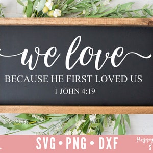 May include: A wooden sign with a black background and white text that reads "we love because he first loved us 1 John 4:19".