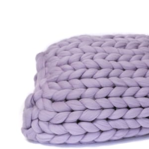 Peut inclure: Un grand coussin de canapé en tricot épais de couleur lavande douce. Le coussin est fait de fil épais et moelleux et a un aspect décontracté et détendu.