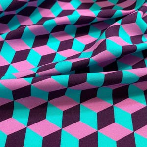 Op de afbeelding: Een stof met een herhalend geometrisch patroon van driedimensionale kubussen in tinten helder turquoise, lichtpaars en donkerpaars. Het textiel vertoont een consistent isometrisch ontwerp met plooien die diepte en textuur creëren.