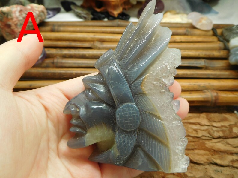Puede incluir: Una escultura tallada en piedra de &aacute;gata gris de un jefe nativo americano con tocado. La piedra tiene una formaci&oacute;n de cristal natural en el lateral.
