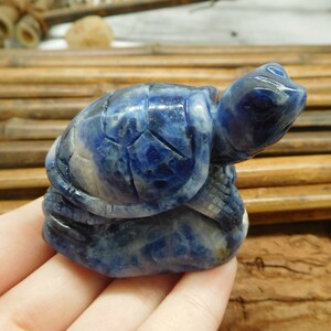 May include: A blue and white carved turtle figurine made of lapis lazuli stone. The turtle is sitting on its hind legs with its head raised.