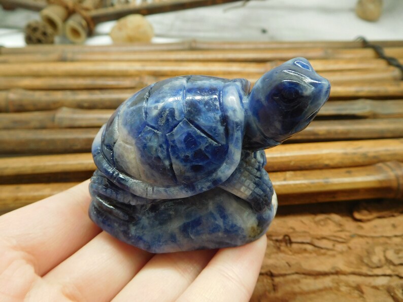 May include: A blue and white carved turtle figurine made of lapis lazuli stone. The turtle is sitting on its hind legs with its head raised.