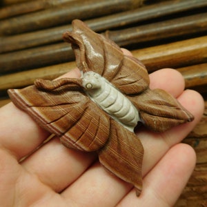 May include: A carved butterfly figurine made of brown and white banded agate. The butterfly has detailed wings and a white body.