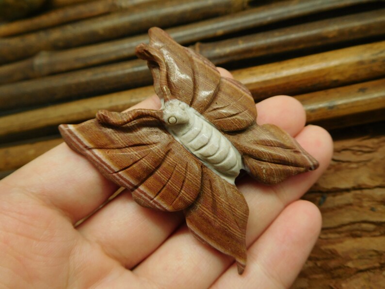 May include: A carved butterfly figurine made of brown and white banded agate. The butterfly has detailed wings and a white body.