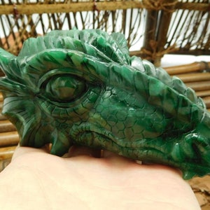 Puede incluir: Escultura de cabeza de drag&oacute;n de jade verde con detalles intrincados. El ojo del drag&oacute;n est&aacute; tallado con un aspecto realista.