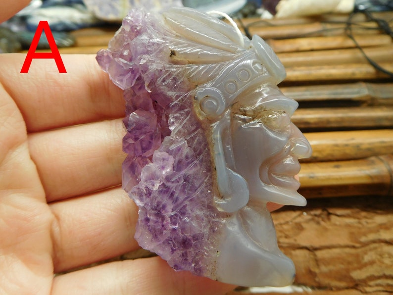 Puede incluir: Un colgante tallado en amatista y &aacute;gata con un perfil detallado de una cara con un tocado. El colgante es de color morado claro y gris.