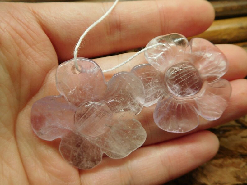 May include: Two translucent lavender flower-shaped pendants with a white string threaded through the top hole of each pendant.
