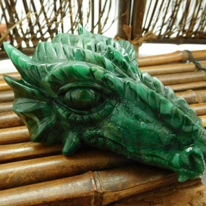 Puede incluir: Escultura de cabeza de drag&oacute;n de jade verde con tallado detallado. El ojo del drag&oacute;n es de color verde oscuro y las escamas son visibles.
