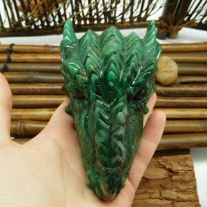 Puede incluir: Escultura de cabeza de drag&oacute;n verde tallada en malaquita. El drag&oacute;n tiene escamas detalladas y una superficie texturizada.