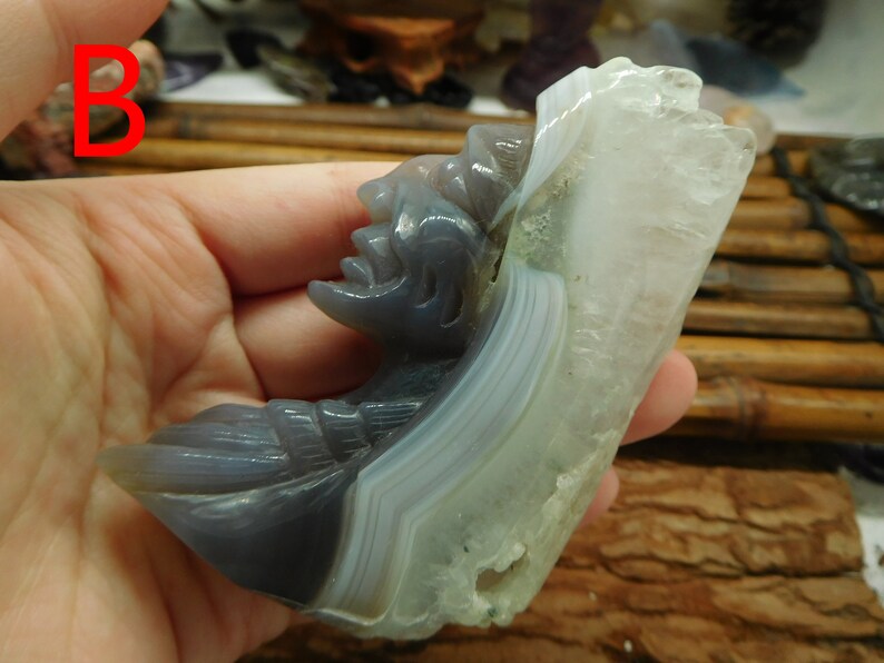 Puede incluir: Una escultura de &aacute;gata tallada de una cara con un fondo de &aacute;gata blanca. La escultura est&aacute; tallada en forma de media luna y tiene una cara detallada con una nariz y una boca prominentes.