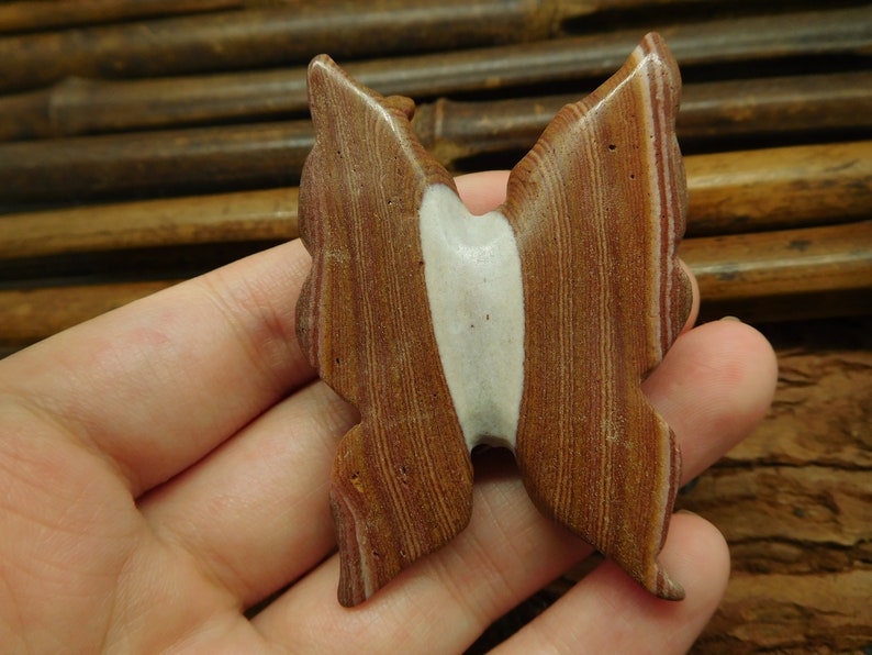 May include: A brown and white butterfly-shaped stone pendant with a layered, striped pattern.