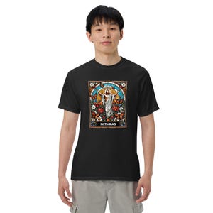 May include: Black t-shirt with a stained glass image of a figure with outstretched arms surrounded by butterflies and flowers. The image is labeled "Mithras".