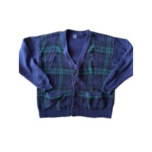 May include: A navy blue and dark green plaid knit cardigan with a V-neckline, long sleeves, and a button-front closure. The garment features two front patch pockets, ribbed cuffs and hem, and a GAP brand label at the inner neckline.