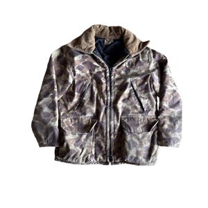 May include: Camouflage hunting jacket with a brown corduroy collar and a zipper closure. The jacket has two large pockets on the front and a patch on the left chest with the words "Red Head" in a circle.