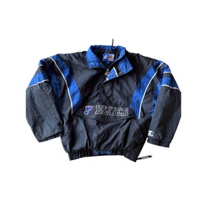 May include: A black and blue St. Louis Blues Starter pullover jacket. The jacket features blue accents on the sleeves and collar, with the team name "Blues" embroidered on the front. The jacket has a snap-button collar and a Starter logo.