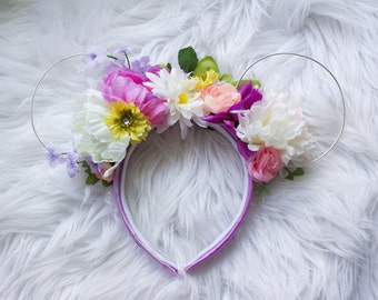 Peut inclure: Un serre-tête violet avec un arrangement floral de fleurs roses, blanches, jaunes et violettes. Le serre-tête a des boucles de fil argenté de chaque côté.
