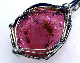 Könnte beinhalten: Ein Anhänger aus rosa Turmalin mit einer Silberdrahtfassung. Der Anhänger ist ein einzigartiges und wunderschönes Schmuckstück.