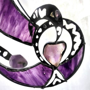 Könnte beinhalten: Ein Buntglas-Sonnenfänger mit einem violetten und schwarzen Design. Der Sonnenfänger hat ein großes herzförmiges Stück Amethyst in der Mitte.