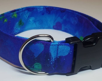 Könnte beinhalten: Ein blaues Hundehalsband mit einem silbernen D-Ring und einer schwarzen Kunststoffschnalle. Das Halsband hat einen blauen und grünen abstrakten Druck mit Herzen.