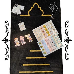 May include: A black prayer mat with gold detailing, a gold mosque motif, and a fringed edge. The image includes stickers, a keychain, and prayer beads. The text "Eid Mubarak" is visible on the stickers.