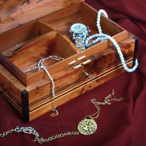 thuya jewelry box in use, a watch and necklaces and bracelets placed in the compartments