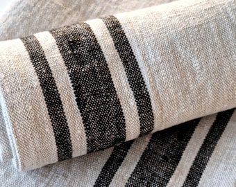 May include: Two linen tea towels with black stripes. The towels are folded and stacked on top of each other.