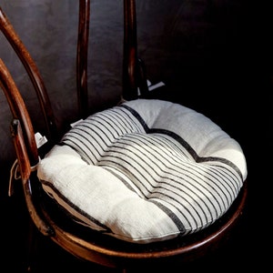 Könnte beinhalten: Ein Holzstuhl mit einem schwarz-weiß gestreiften Kissen. Der Stuhl ist aus dunklem Holz und hat eine geschwungene Rückenlehne.