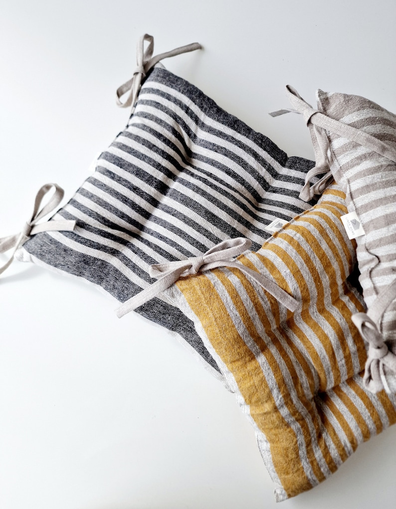 Puede incluir: Dos cojines de silla de lino a rayas con lazos. Un coj&iacute;n es negro y blanco, el otro es amarillo y blanco.