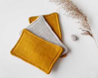 May include: Three rectangular fabric coasters. Two are a light gray waffle weave fabric and one is a mustard yellow linen fabric.