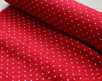 May include: Red fabric with white polka dots. The fabric is rolled up and the polka dots are visible on both the rolled and unrolled portions.