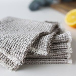 May include: A stack of gray waffle weave kitchen towels with a frayed edge.