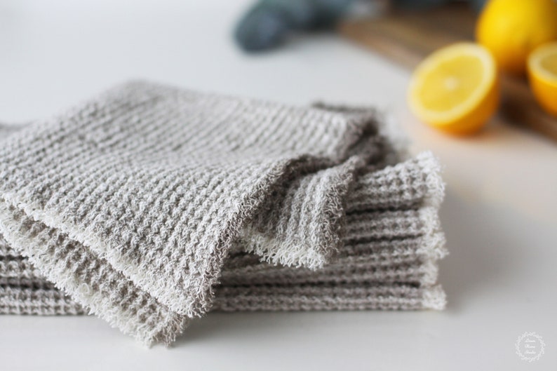 May include: A stack of gray waffle weave kitchen towels with a frayed edge.