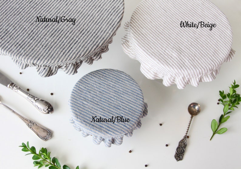 Three striped linen bowl covers showing available patterns: Natural/Gray, Natural/Blue, and White/Beige. Reusable fabric dish covers with elastic ruffles, displayed with vintage silverware. Zero waste kitchen storage options for eco-conscious homes.