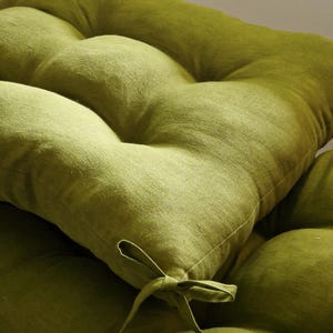 May include: Close-up of a lime green tufted cushion. The cushion has a textured fabric and a tied bow detail. The cushion is a soft, comfortable seating accessory.