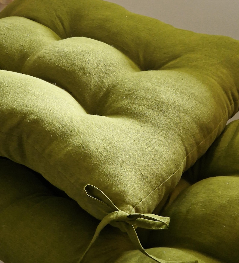May include: Close-up of a lime green tufted cushion. The cushion has a textured fabric and a tied bow detail. The cushion is a soft, comfortable seating accessory.