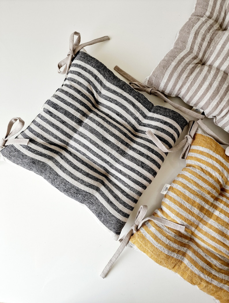 Puede incluir: Tres cojines de silla a rayas con lazos. Los cojines est&aacute;n hechos de tela de lino y tienen un dise&ntilde;o acolchado. Los cojines son de rayas negras y blancas, beige y blancas, y amarillas y blancas.